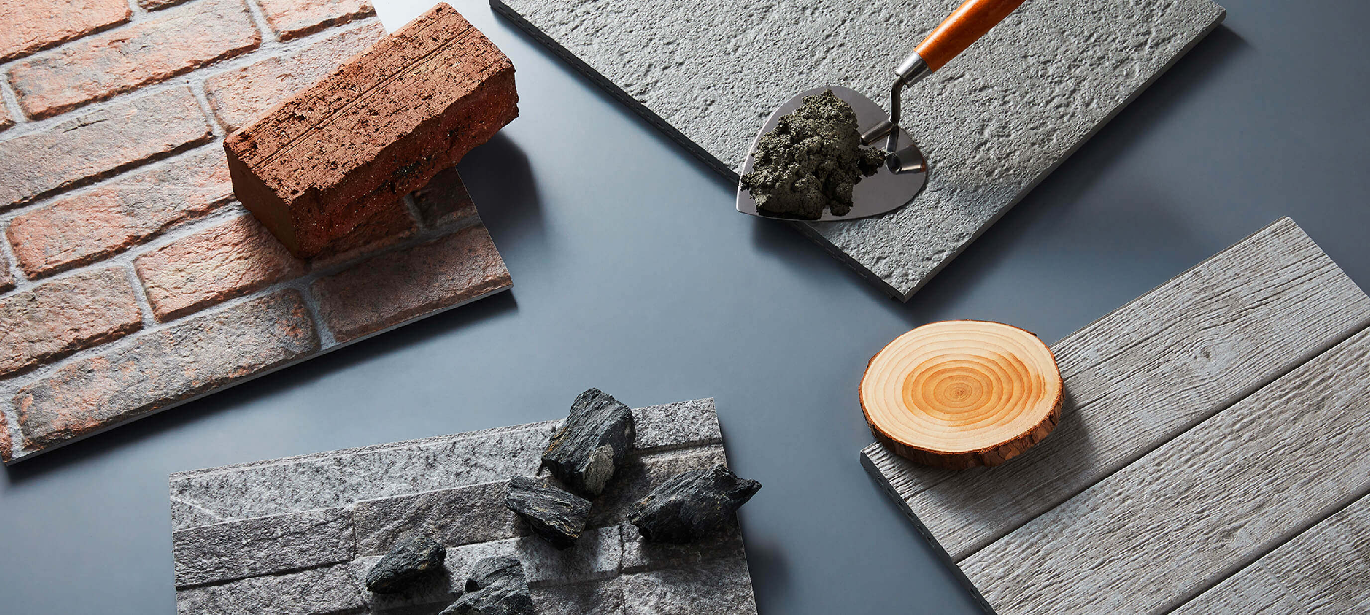 KMEW facade panels photographed alongside real brick, stone, and concrete, showcasing realistic reproduction of natural textures and design.