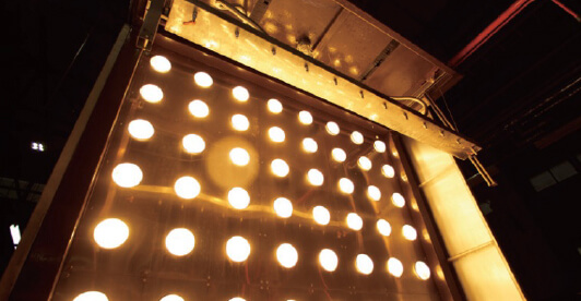 Testing process where strong light is directed onto a panel to evaluate colour fading and weather resistance