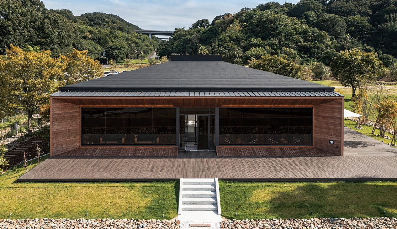 A brown-toned house harmoniously blending into nature, with a dark KMEW roof reflecting modern design